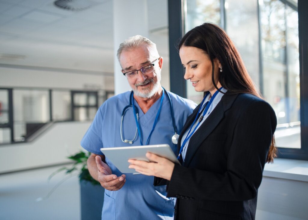 Junge Pharmazeutin, die einem Arzt im Krankenhaus etwas erklärt.